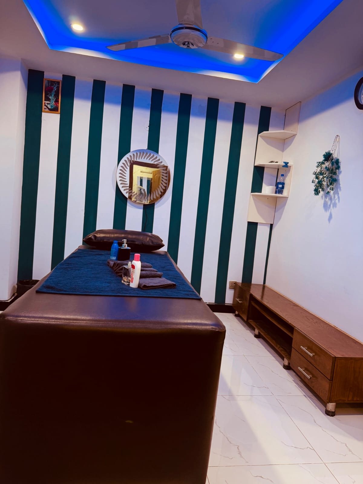 Massage bed with fresh towels in a green and white striped room
